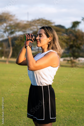Latin woman standing on a golf course using a rangefinder, focusing on her next shot with concentration and enjoyment