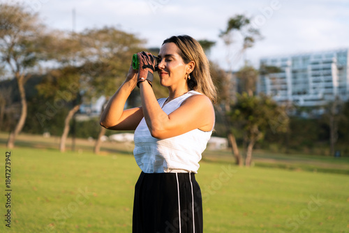 Latin hispanic woman focusing on the golf course with a rangefinder, wearing a golf glove, enjoying a sunny day outdoors