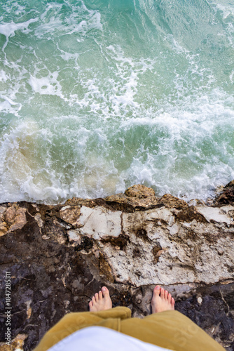 Barefoot on Rugged Coastal Edge Over Turquoise Ocean Waves for Adventure and Travel Photo