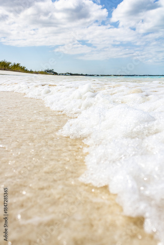 Calm Beach Shore With White Foam Cresting On Golden Sand And Clear Blue Sky