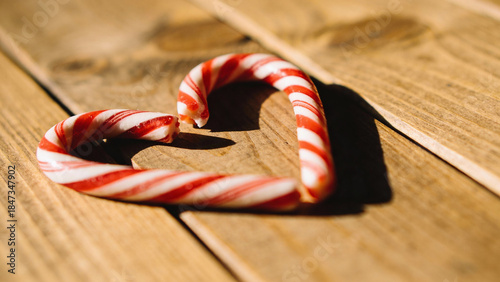 Candy canes forming a heart shape on wooden background  