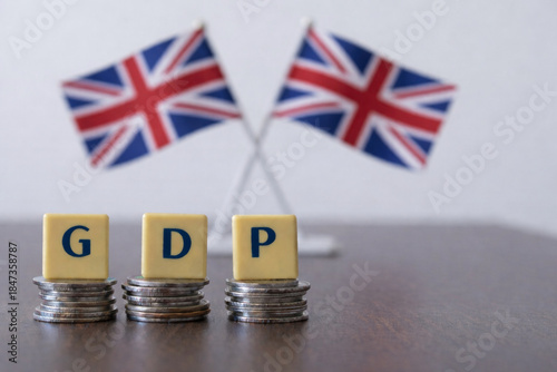 United Kingdom GDP concept with stacked coins and blurred Union Jack flags, symbolizing national output, growth, global ranking, IMF and United Nations assessments, trade strength and long performance