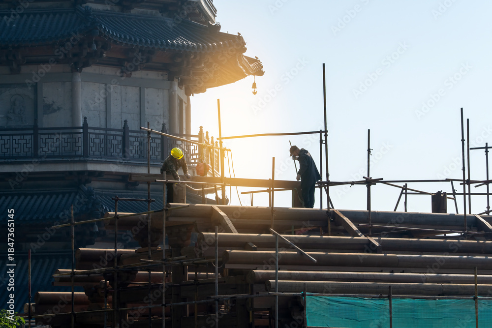 Fototapeta premium Construction Workers on Scaffolding Near Historic Building