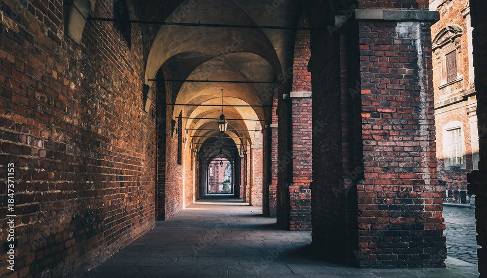 Fototapeta premium Covered brick archway corridor with hanging lamps and columns, leading to a street.