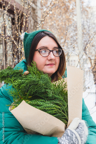 A girl holds a bouquet with coniferous branches
