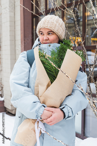 A girl holds a bouquet with coniferous branches