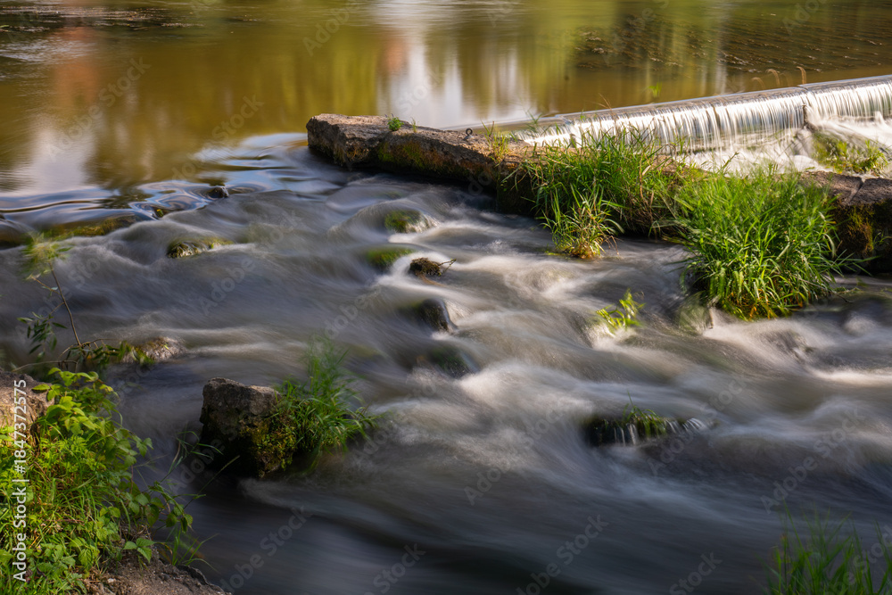 Obraz premium Silky Smooth Water Flowing Over a Small Stone Weir (Long Exposure)