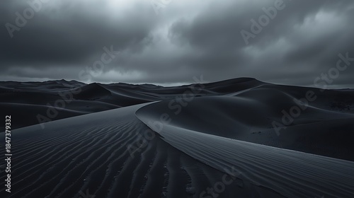 Eerie Charcoal Dunes Under a Turbulent Sky: Monochromatic Desert Landscape with Intricate Sand Ripples and Dramatic Contrasting Ridges, Capturing Vast Isolation and Mystery.