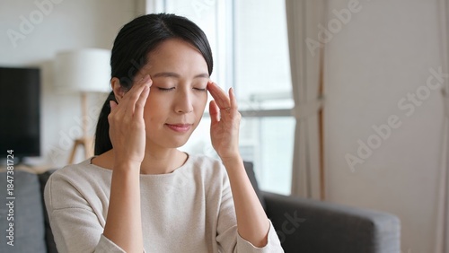 リビングで頭痛に悩まされこめかみを押さえる女性