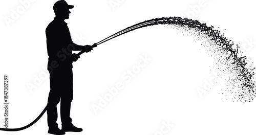 Silhouette of a man spraying water from a hose