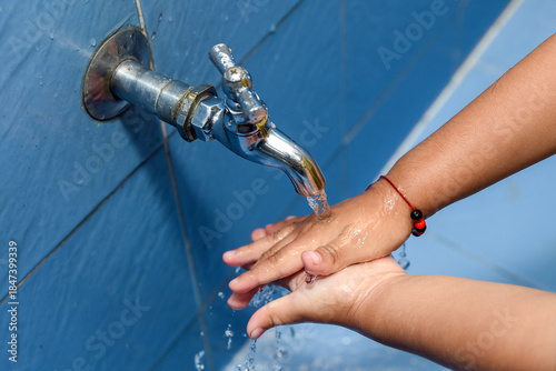 Close-up of hands washing under running water from a faucet, promoting hygiene, sanitation, cleanliness, health care, disease prevention, and daily personal care routine.