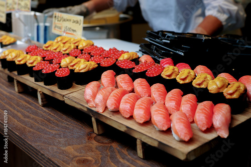 Many pieces of sushi made from salmon and unagi on the wooden tray for selling
