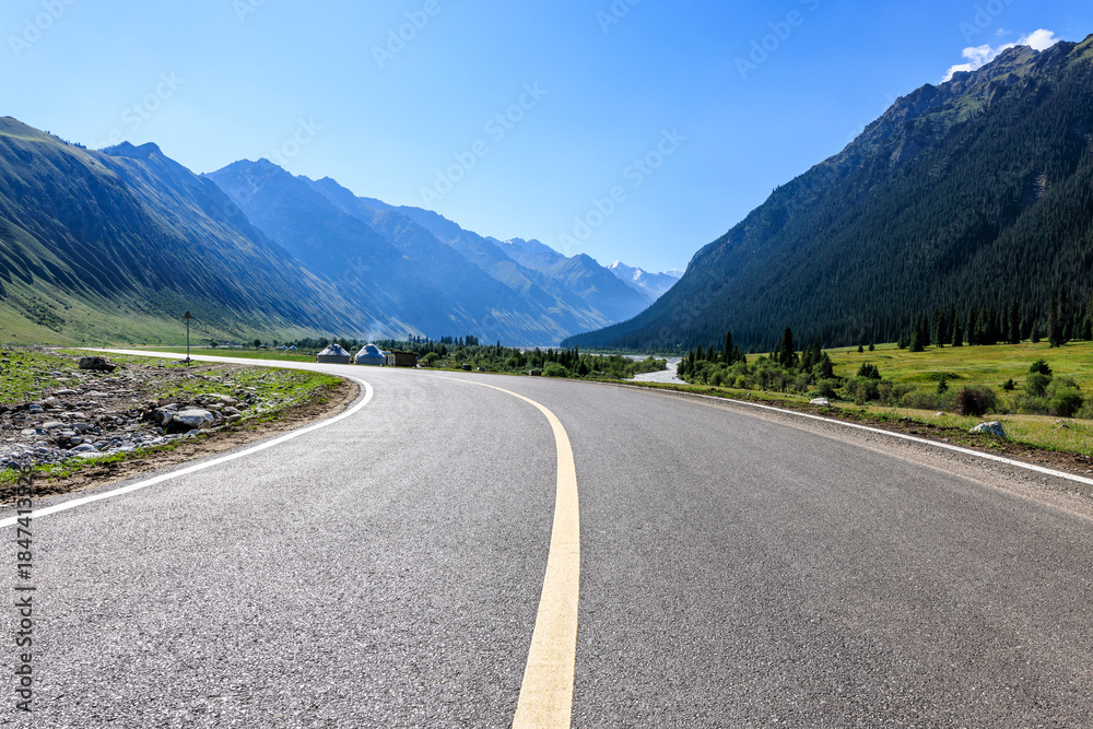Fototapeta premium Winding asphalt road and green mountain natural landscape under blue sky