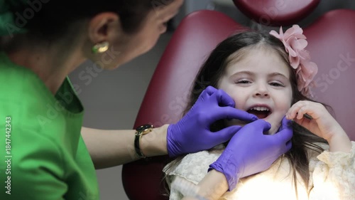 Pediatric dentist teaching a little girl how to brush teeth