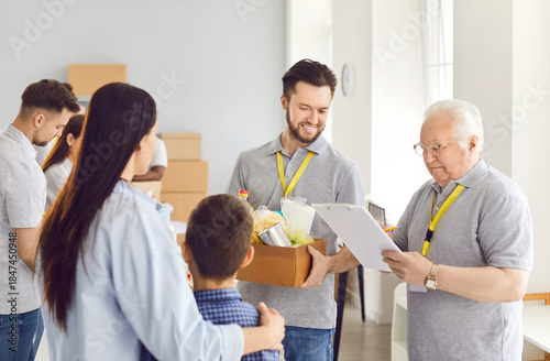 Group of volunteers working at charity center giving free food donations for people in need in charitable foundation. Humanitarian aid, volunteering and social help for poor concept.