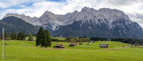 Photos Scenic panoramic landscape of wide open meadow with small barns and mountains at