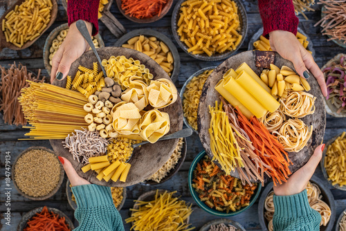 Different types of uncooked pasta at the hands of two women.