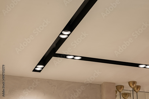 Suspended ceiling with halogen spots lamps and drywall construction in empty room in apartment or house. Stretch ceiling white and complex shape.