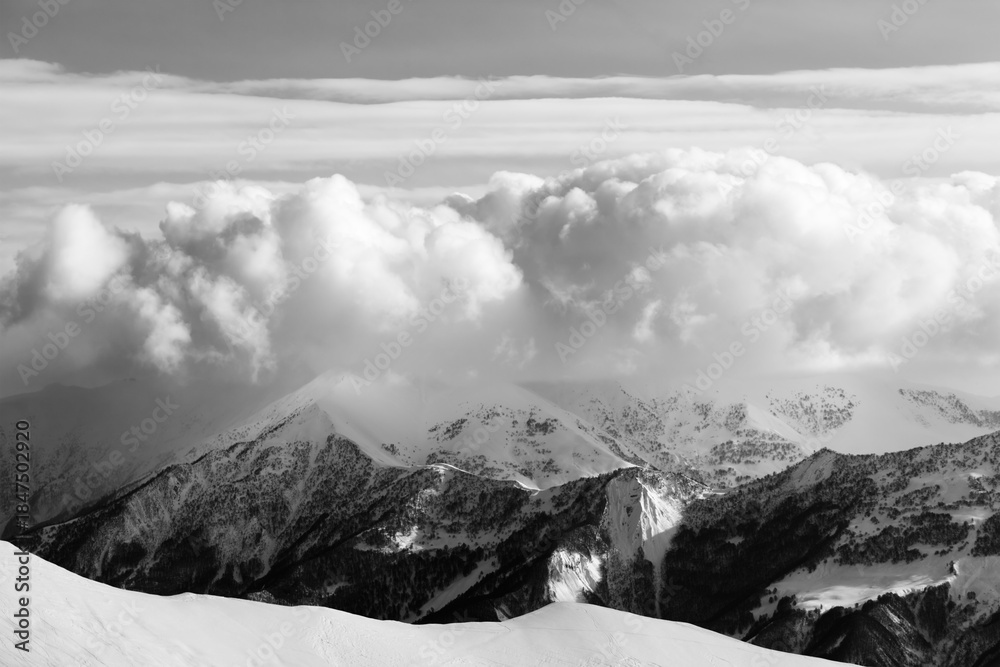 Obraz premium Black and white snowy mountains in clouds and off-piste slope