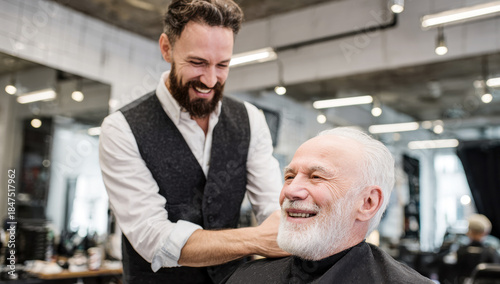 Barber giving senior client a haircut and beard trim, both laughing and enjoying the barbershop service