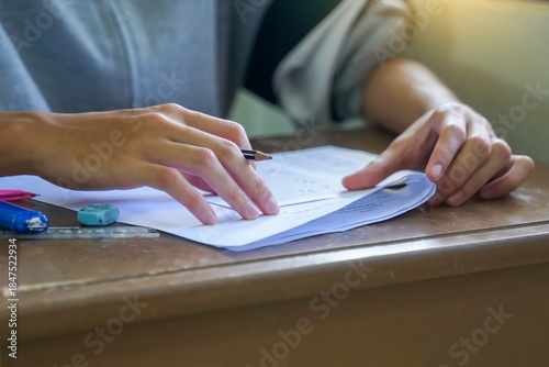 High school or university students sitting in a classroom, focused on writing their answers on examination papers during a final test or assessment.