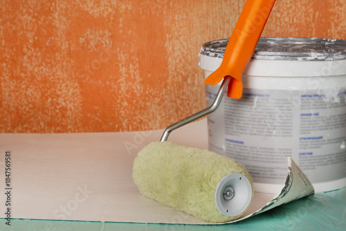 Paint, roller, and brush ready for an apartment renovation. Tools for the room renovation are displayed against an old wall. Apartment renovation concept