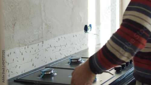 Worker Installing Built-in Kitchen Stove on Countertop