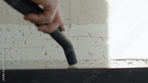 Worker Using Vacuum Cleaner to Remove Dust from Kitchen Countertop After Drilling