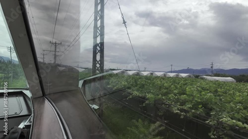 The train travels through the countryside, with pastoral views and dense clouds outside the window.