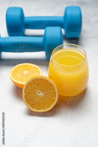 Healthy Lifestyle Concept with Dumbbells and Fresh Orange Juice on Light Background, Fitness and Wellness