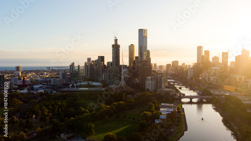 Aerial view of Melbourne's skyline bathed in the warm glow of the setting sun, Yarra River reflecting the light, Melbourne, Victoria, Australia.