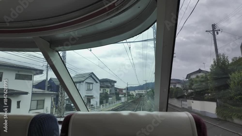 Fixed-camera shot from the sightseeing carriage of a train, capturing the townscape outside the window.