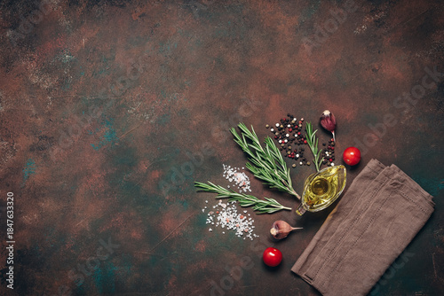 Dark grunge background with cooking ingredients, spices, herbs, and olive oil. Top view, flat lay, copy space.