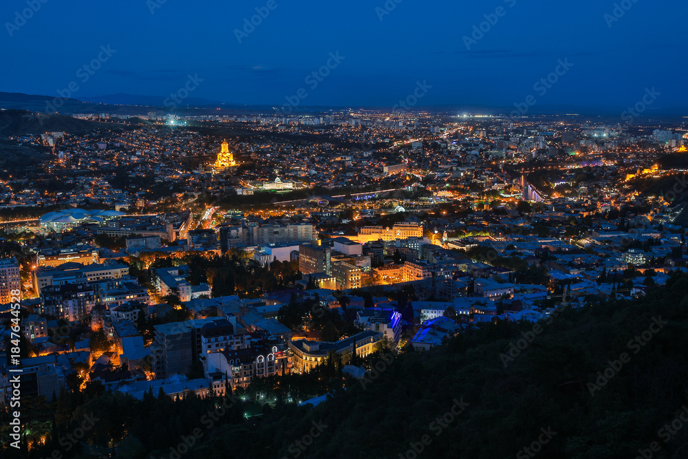 Fototapeta premium Panoramic Night View of Illuminated Tbilisi Cityscape and Sameba Cathedral
