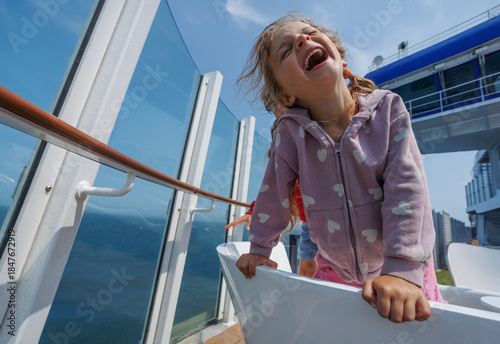Girl with a big smile is leaning over on ferry crossing channel