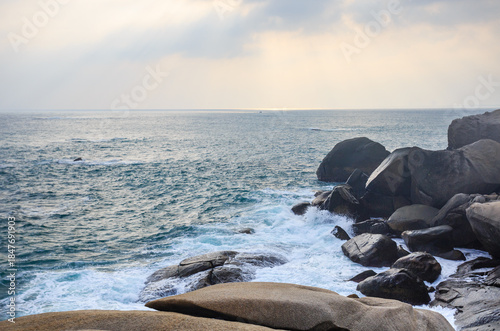 The scenery of Stone Park in Hainan, China, features emerald-green seawater crashing against the rocks, creating beautiful waves.