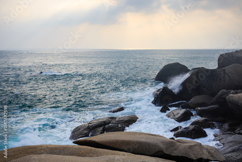 The scenery of Stone Park in Hainan, China, features emerald-green seawater crashing against the rocks, creating beautiful waves.