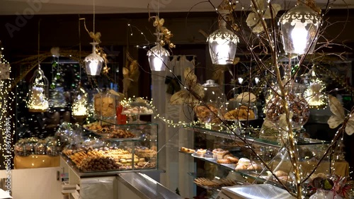 Italy, Volpiano, 11-21-2025. Interior pastry shop with pastries and sweets in Christmas time. Christmas decorations. Panning 4K