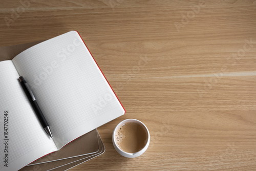 modern wooden desk setup from above with blank notebook ready for notes, a pen, and coffee. minimalist desktop with copy