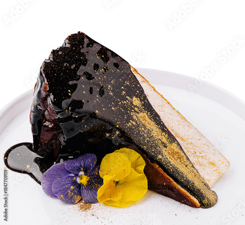 Chocolate cake slice with colorful edible flowers on a white plate