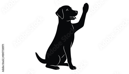 A black dog sits and raises its paw as if to say hello.