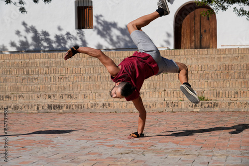 Man breakdancing a handstand freeze on urban bricks