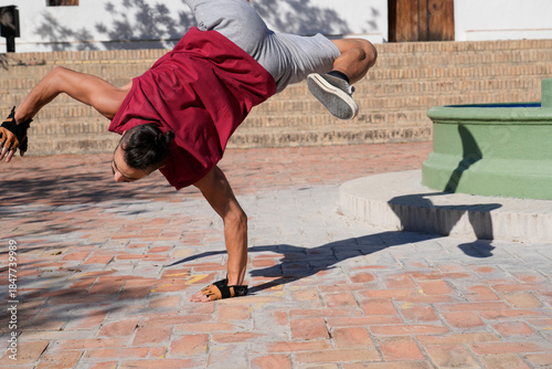 Man breakdancing a handstand freeze on urban bricks