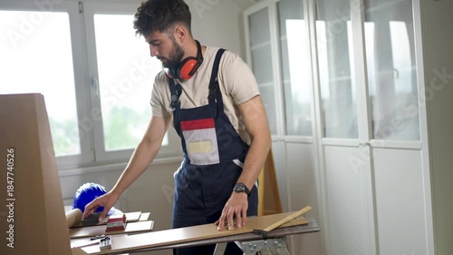 A young man working with wood in a modern workshop, focused on crafting and woodworking.