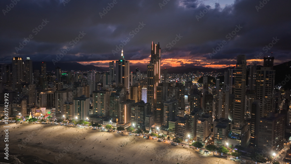 Fototapeta premium Aerial View of Balneario Camboriu Cityscape at Dusk with Illuminated Skyscrapers and Beach