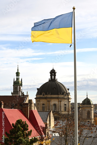 Ukrainian flag flutters in the wind on the background the city of Lviv, Ukraine. Lviv panorama.