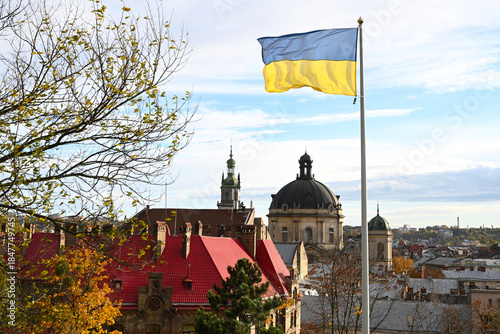Ukrainian flag flutters in the wind on the background the city of Lviv, Ukraine. Lviv panorama.