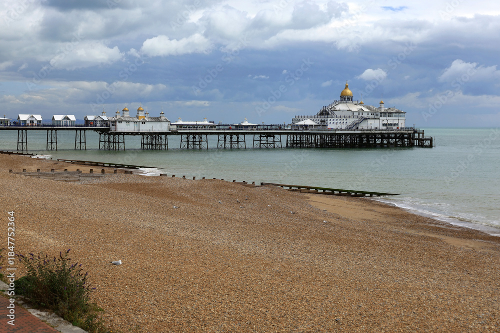 Fototapeta premium Photo with a view of the Eastbourne Pier, the beach and the English Channel against a stormy sky in Eastbourne, United Kingdom