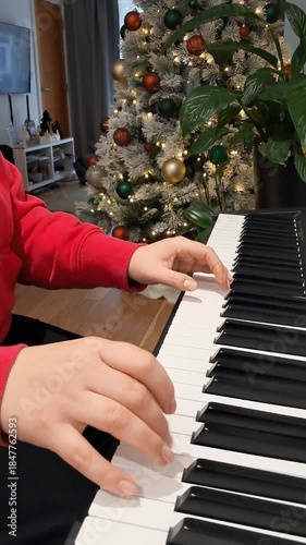 Elegant hands of pianist playing piano near Christmas tree during festive concert