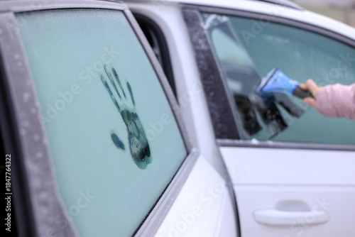 Frozen windows on a car and scraping the frozen window with a scraper on a frosty morning